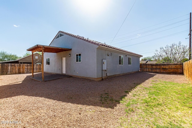 rear view of house with a tiled roof, a patio area, a fenced backyard, and stucco siding