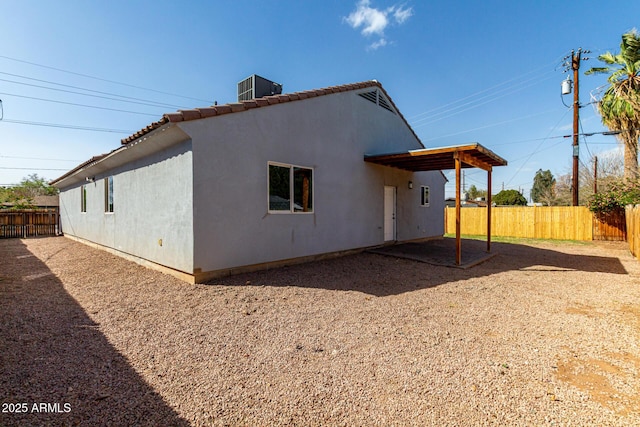 back of house featuring a tiled roof, cooling unit, a fenced backyard, and stucco siding