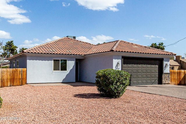 view of front facade featuring fence, a tile roof, stucco siding, driveway, and an attached garage