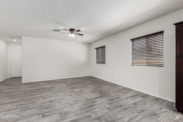 spare room with light wood finished floors, visible vents, baseboards, and ceiling fan