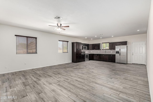 unfurnished living room featuring a wealth of natural light, visible vents, light wood-style floors, and a ceiling fan