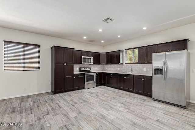 kitchen featuring stainless steel appliances, dark brown cabinetry, decorative backsplash, and light countertops