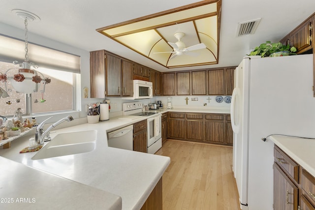 kitchen with sink, white appliances, decorative light fixtures, ceiling fan, and light hardwood / wood-style floors