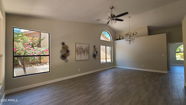 empty room featuring vaulted ceiling, dark hardwood / wood-style floors, and ceiling fan with notable chandelier