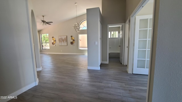 interior space with dark wood-type flooring, high vaulted ceiling, and ceiling fan with notable chandelier