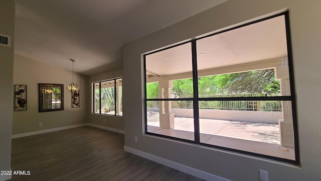 spare room featuring an inviting chandelier, lofted ceiling, and dark hardwood / wood-style flooring