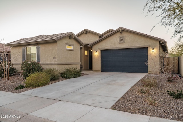 ranch-style house with a garage, a tiled roof, concrete driveway, and stucco siding