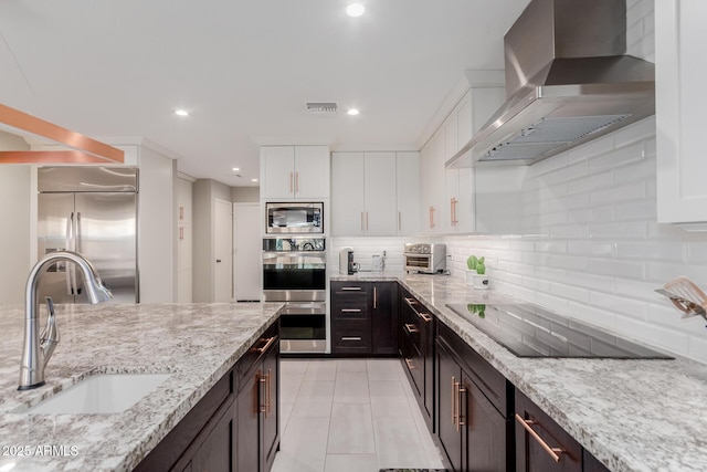 9921 E Doubletree Ranch Rd, Scottsdale, AZ 85258 - kitchen featuring wall chimney range hood, built in appliances, white cabinetry, recessed lighting, and tasteful backsplash