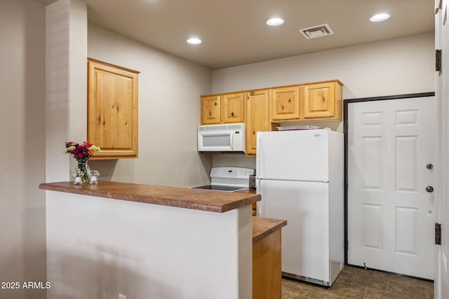 kitchen with white appliances, visible vents, a peninsula, light brown cabinetry, and recessed lighting