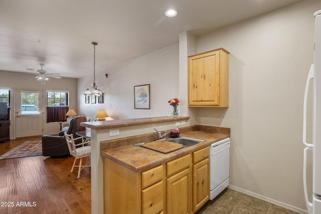 kitchen with white appliances, baseboards, open floor plan, light brown cabinets, and a sink