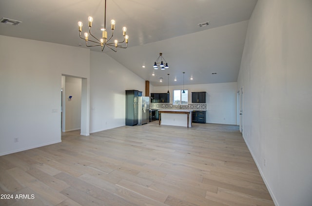 unfurnished living room with light hardwood / wood-style flooring, high vaulted ceiling, and an inviting chandelier