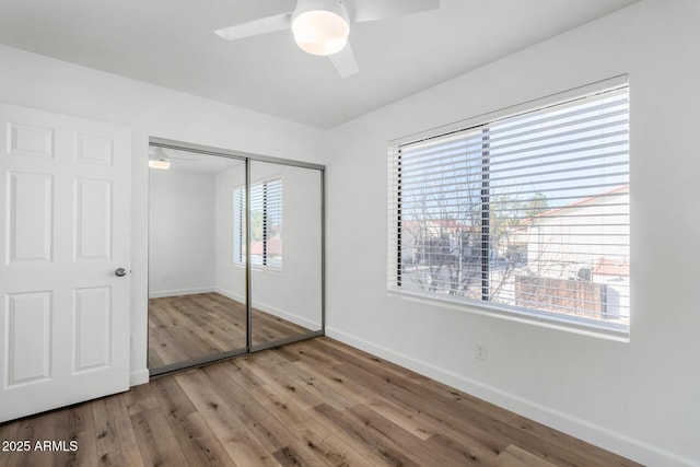 unfurnished bedroom featuring a closet, ceiling fan, baseboards, and wood finished floors