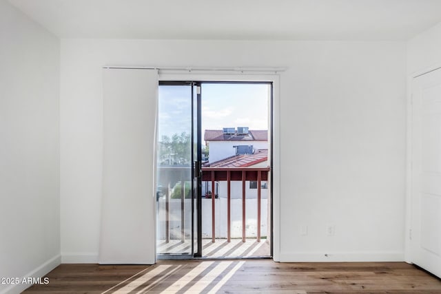 doorway with baseboards and wood finished floors