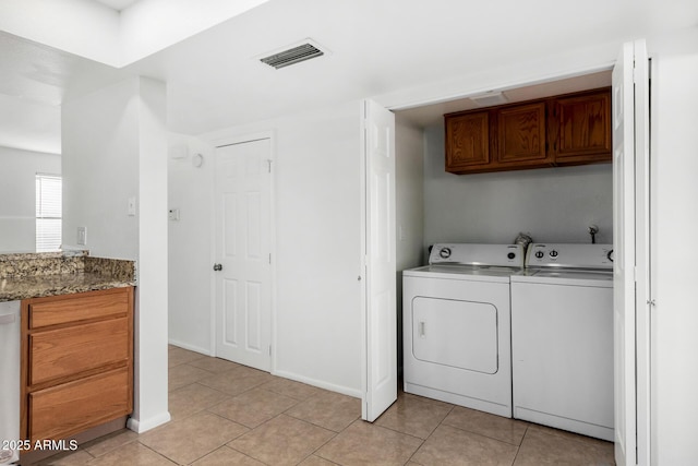 washroom with light tile patterned flooring, cabinet space, visible vents, and washer and dryer