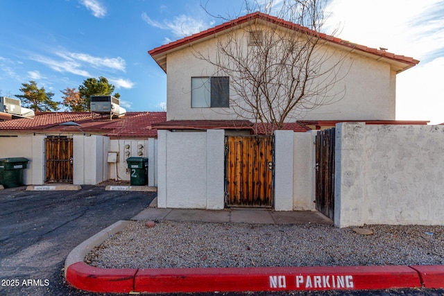 view of front of house with central AC, a gate, and stucco siding