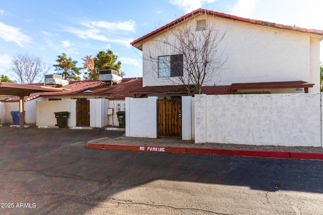 exterior space featuring central air condition unit, stucco siding, a gate, fence, and a tiled roof