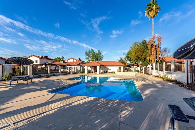 community pool with a patio and fence