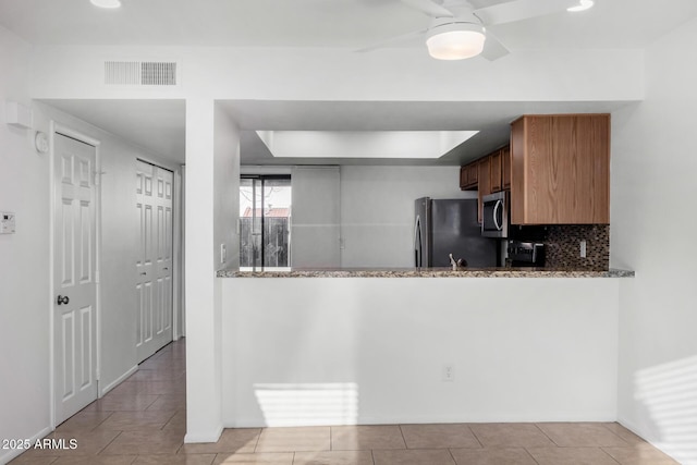 kitchen featuring stone counters, tasteful backsplash, visible vents, appliances with stainless steel finishes, and ceiling fan