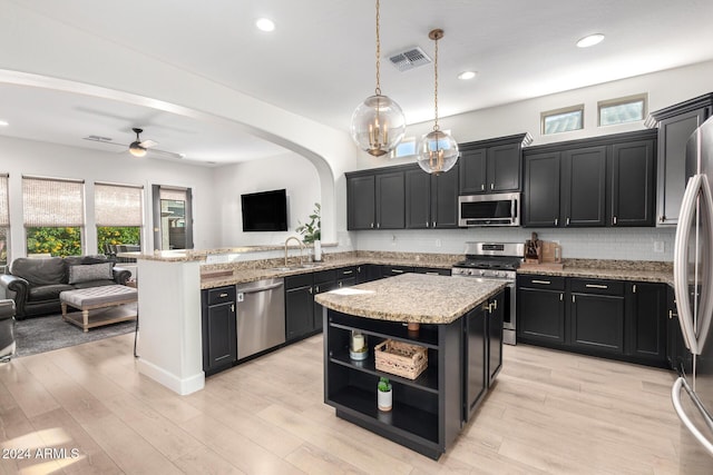 kitchen with kitchen peninsula, stainless steel appliances, ceiling fan, decorative light fixtures, and a kitchen island