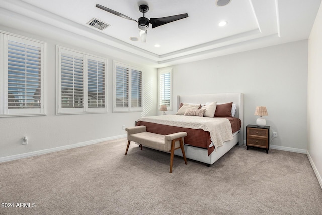 carpeted bedroom featuring a tray ceiling and ceiling fan