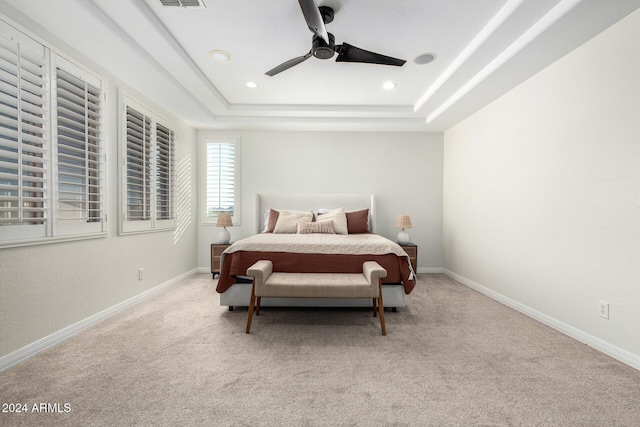 carpeted bedroom featuring ceiling fan and a tray ceiling