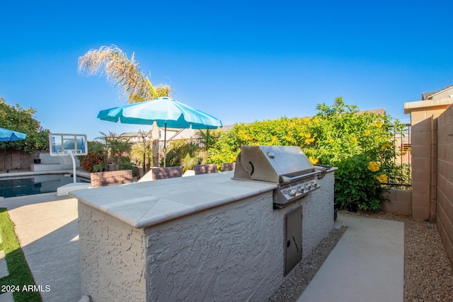 view of patio featuring an outdoor kitchen, a fenced in pool, and area for grilling