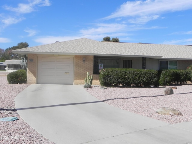 ranch-style home featuring a shingled roof, brick siding, driveway, and an attached garage