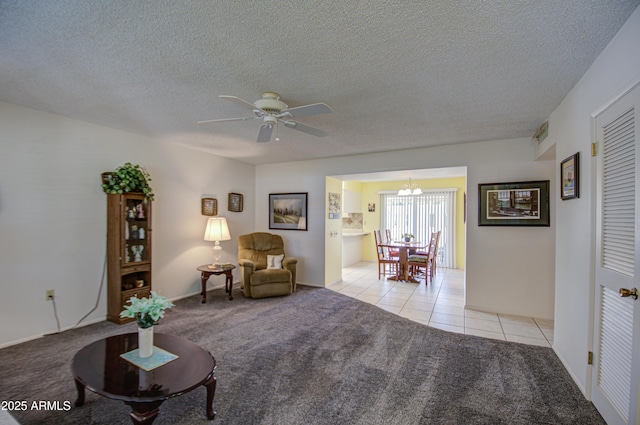 sitting room with ceiling fan with notable chandelier, light colored carpet, a textured ceiling, and light tile patterned floors