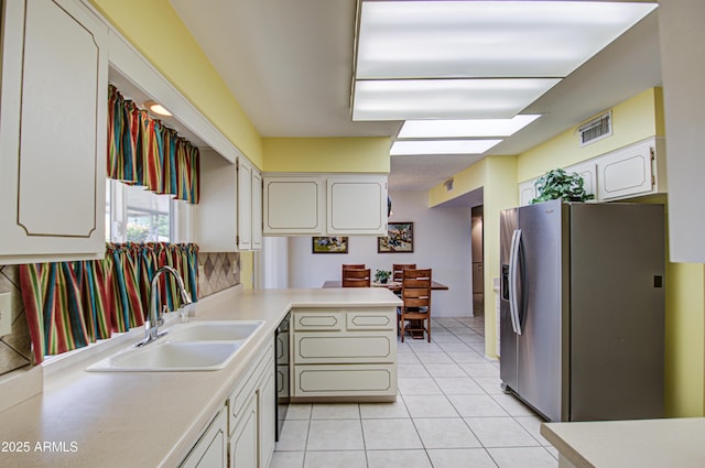 kitchen featuring light tile patterned floors, a sink, visible vents, light countertops, and stainless steel fridge with ice dispenser