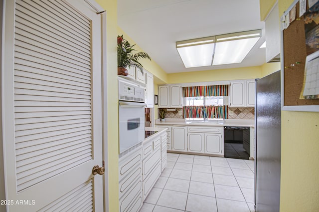 kitchen featuring light tile patterned floors, tasteful backsplash, light countertops, a sink, and black appliances