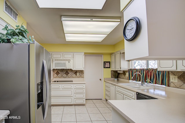 kitchen with light tile patterned floors, stainless steel fridge, visible vents, white microwave, and a sink