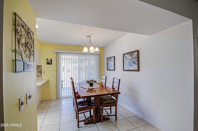 dining area with light tile patterned floors, baseboards, a textured ceiling, and an inviting chandelier