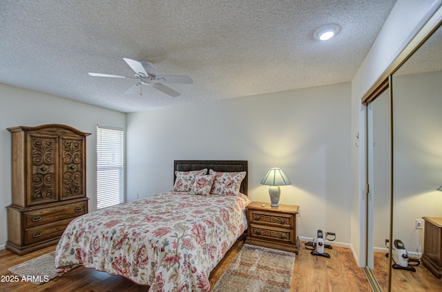 bedroom with baseboards, a ceiling fan, wood finished floors, a textured ceiling, and a closet