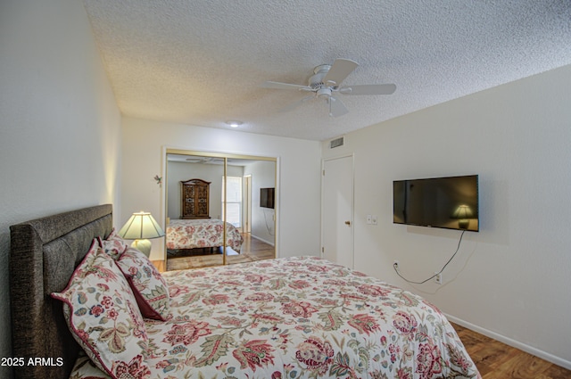 bedroom featuring visible vents, a ceiling fan, wood finished floors, a textured ceiling, and a closet