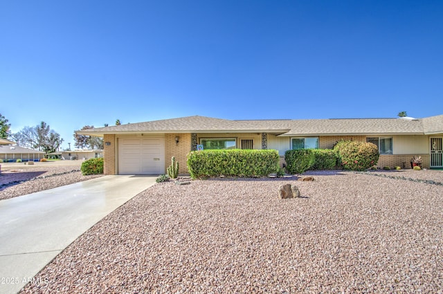 ranch-style house with a garage, a shingled roof, concrete driveway, and brick siding