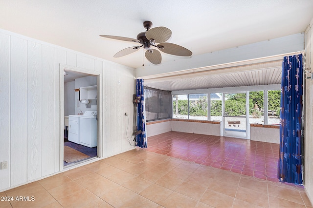 unfurnished room featuring washer / clothes dryer, wooden walls, tile patterned floors, and ceiling fan