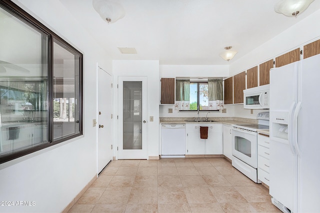 kitchen featuring sink, white appliances, and light tile patterned flooring