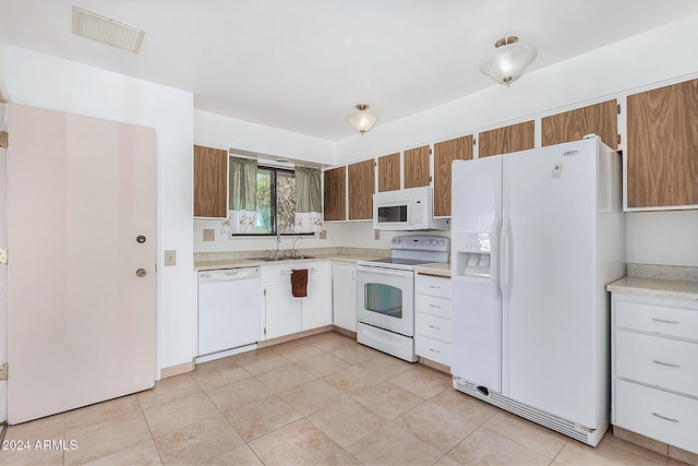 kitchen with white cabinets, light tile patterned floors, white appliances, and sink