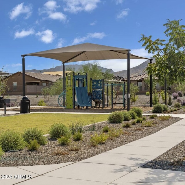 surrounding community featuring a playground, a mountain view, and a yard