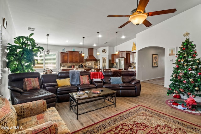 living room with ceiling fan, light hardwood / wood-style floors, and vaulted ceiling