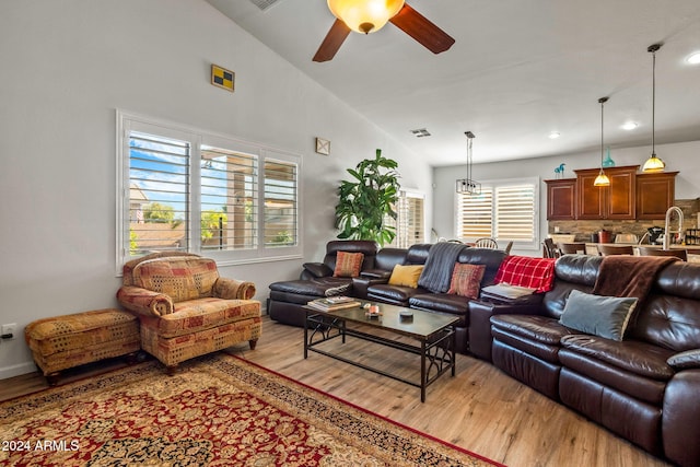 living room with light hardwood / wood-style floors, vaulted ceiling, and a healthy amount of sunlight