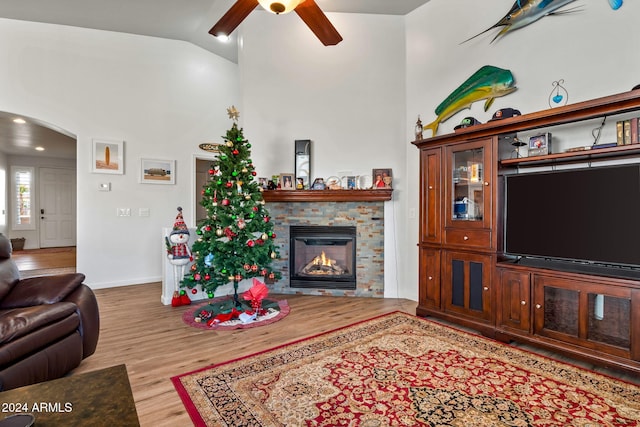 living room featuring a fireplace, ceiling fan, light hardwood / wood-style flooring, and lofted ceiling