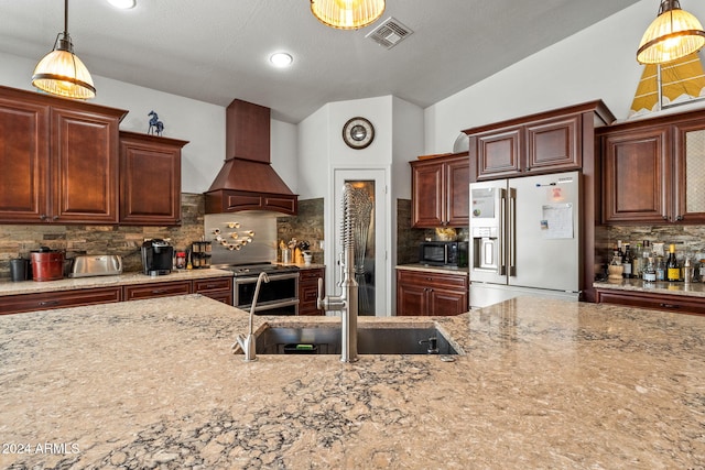 kitchen with custom exhaust hood, hanging light fixtures, vaulted ceiling, appliances with stainless steel finishes, and tasteful backsplash