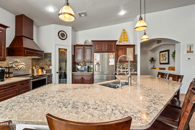 kitchen featuring custom range hood, vaulted ceiling, appliances with stainless steel finishes, and a large island