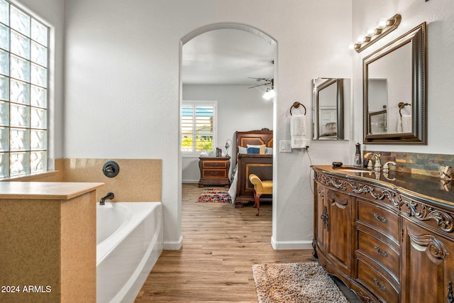 bathroom with a bath, wood-type flooring, vanity, and ceiling fan