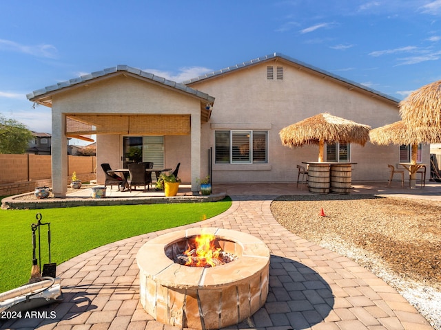 back of property featuring a yard, a patio, and a fire pit