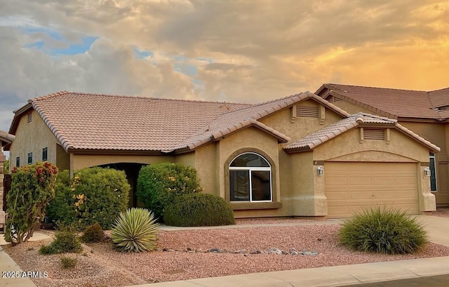 view of front of house featuring stucco siding, concrete driveway, an attached garage, and a tiled roof