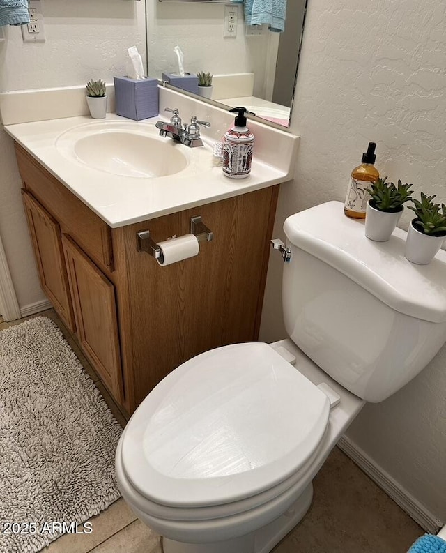 bathroom with toilet, vanity, and a textured wall