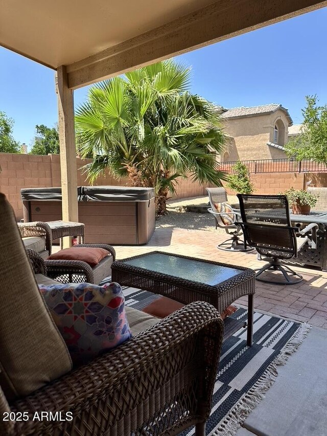 view of patio featuring a hot tub, outdoor dining space, and a fenced backyard