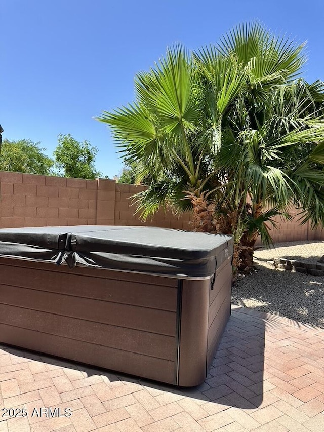 view of patio / terrace featuring a hot tub and fence